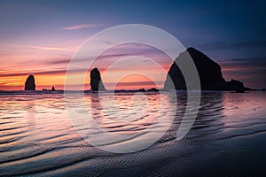 Ripples and sunset reflection in front of Cannon beach haystack