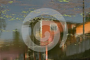 Reflection of houses in the water. Surface of a city pond.