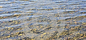 Ripples on water at beach with rocks beneath photo