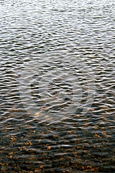 Ripples on water, calmness on river, view of reservoir from the shore. Vertical view, selective focus