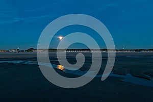 Rise of the full moon over the beach during blue hour