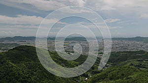 Rise up over green hills to reveal sprawling Kochi City in Shikoku, Japan