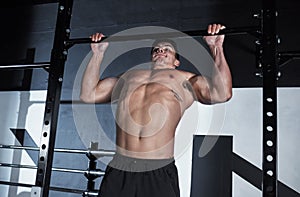 Rise up to every fitness challenge. a young man lifting doing pull ups at a gym.