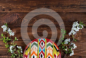 Rishtan Uzbek national plate and blooming cherry flowers on wooden background