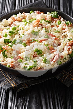 Risi e Bisi classic Italian comfort food of rice with peas and chunks of ham close up in a plate. Vertical