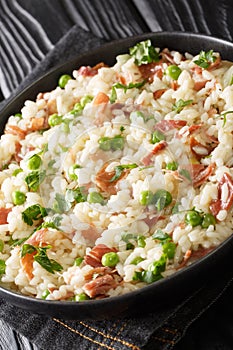 Risi e Bisi Italian Rice and Peas with ham close up in a plate. Vertical photo