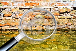 Rising damp on a brick wall in a channel full of water - Concept image seen through a magnifying glass