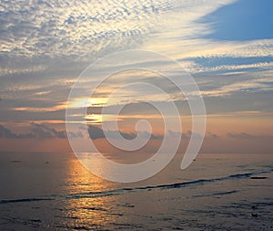 Rising Sun behind Clouds at Horizon with Bright Morning Sky with White Cloud Pattern at Serene Beach