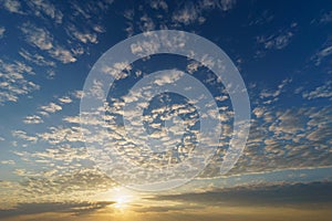 Rising sun over blue sky with cirrocumulus clouds