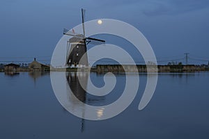 The rising Super Moon behind the windmill Tweemanspolder Nr. 4 with the reflection in the water of the Rottemeren near Zevenhuizen