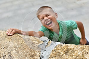 Risk of falling from mountain. child hangs on wall. dangerous games of children