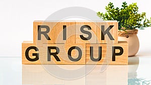 RISK GROUP word written on wood block. Faqs text on table, concept
