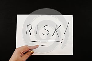 RISK inscription on white. Hand points to the word `risk` written on a white piece of paper.