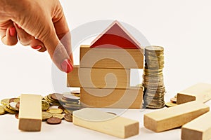 Risk of investing money in real estate projects, conceptual image with house shape from wooden blocks and cash money on white back