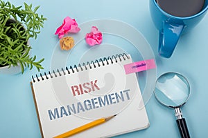 Risk Management concept. Notepad with message, pencil and flower, coffe cup. Office supplies on desk table top view