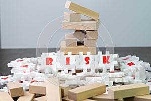 Risk management concept, white puzzle jigsaw with alphabet building the word Risk at the center of dark chalkboard with collapse