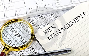 RISK MANAGEMENT text on the notebook with chart, magnifier,keyboard and pen