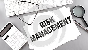 RISK MANAGEMENT text on paper with keyboard, calculator on grey background