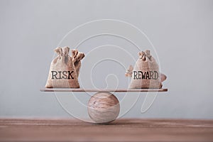 Risk and reward bags on a basic balance scale in equal position. risk management concept, depicts investors use a risk reward photo