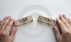 Risk or Reward symbol. Concept word Risk or Reward on wooden blocks. Businessman hand. Beautiful white background. Business and