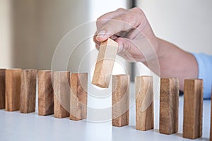 Risk and Strategy in Business, Image of hand gambling placing wooden block on a line of domino, prevention and development to