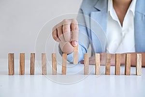 Risk and Strategy in Business, Image of hand gambling placing wooden block on a line of domino, prevention and development to