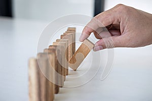 Risk and Strategy in Business, Image of hand gambling placing wooden block on a line of domino, prevention and development to