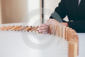 Risk and Strategy in Business, Image of hand stopping falling collapse wooden block dominoes effect from continuous toppled block