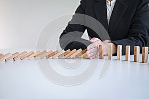 Risk and Strategy in Business, Image of hand stopping falling collapse wooden block dominoes effect from continuous toppled block