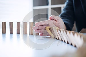 Risk and Strategy in Business, Image of hand stopping falling collapse wooden block dominoes effect from continuous toppled block