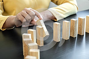 Risk and Strategy in Business, Image of hand stopping falling collapse wooden block dominoes effect from continuous toppled block