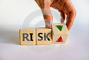 Risk symbol. Wooden cube with word `risk`. Businessman turns the wooden cube, changes the direction of an arrow down or up.