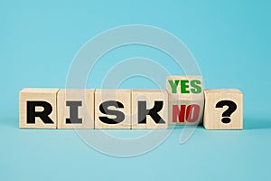 Risk symbol. A wooden cube with the word risk yes or no representing high or low risk. Business and risk concept.