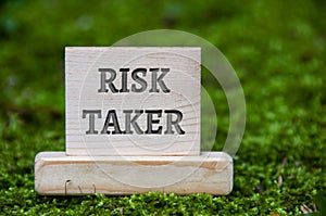 Risk taker text on wooden block with green nature background. Motivational concept
