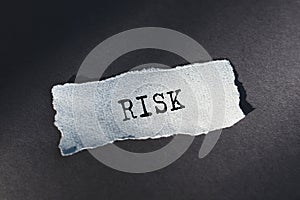 RISK - text on torn paper on dark desk in sunlight