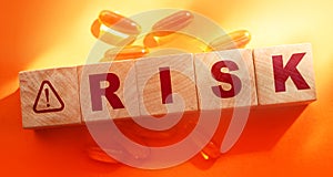 Risk Word on Wooden Cubes, oil capsules on orange. Medical healthcare concept