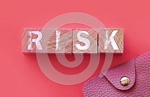 Risk Word On wooden cubes with pink wallet besides on pink background. Business startup risk and crisis management concept