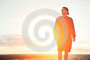 Risky man standing on the top of the roof at sunset