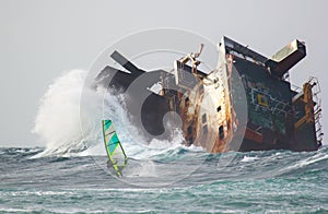 Risky windsurfing in storm on the background of the abandoned ship wrack