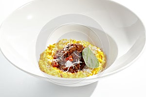 Risotto alla milanese with meat ragu. Saffron risotto with lamb meat isolated on white background. Yellow risotto in white plate.