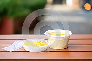 risotto milanese packaged in a to-go container, on a bench outside