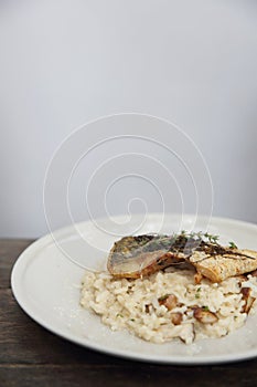 Risotto with sea bass fillet steak on wooden table , italian food