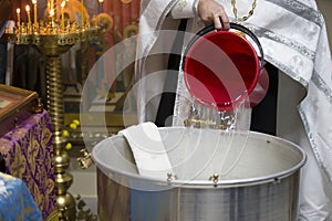 The rite of baptism. Priest prepare to baptize the child. Font for taking faith.Priest pours water into the bath for baptism photo