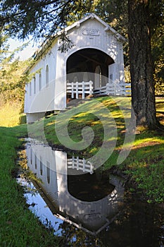 A reflection of Ritner Creek Covered Bridge in a pool of rainwater. photo
