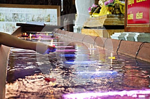 Ritual praying colorful candle floating on water for pray reclining Buddha image at Wat Phra Non Chakkrasi Worawihan in Sing Buri,