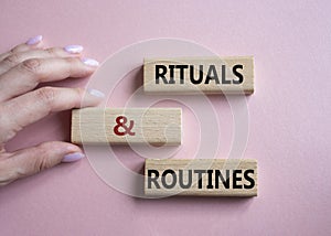 Rituals and Routines symbol. Concept words Rituals and Routines on wooden blocks. Doctor hand. Beautiful pink background.