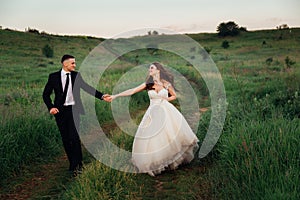 Ritzy bride raises her dress up while walking with groom