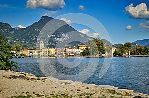 Riva del Garda, Italy- garda lake with Monte Brione, peaks, town, plants, beach, shore, blue sky