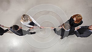Rival business man and woman compete for the command by pulling the rope