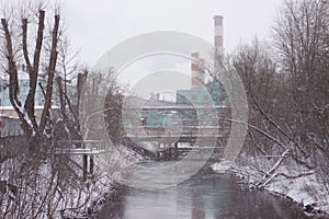 River against the background of factory pipes on a snowy day